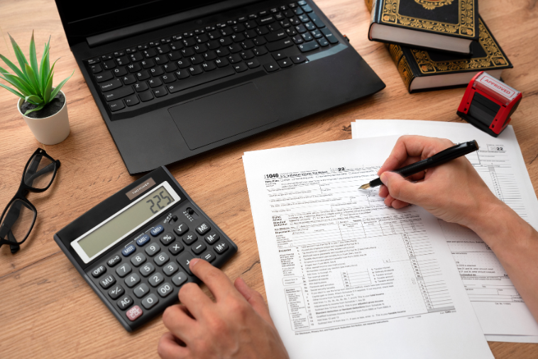 Pc og kalkulator i bruk til skattemeldingen